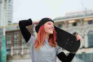 Foto grátis mulher sorridente segurando o plano médio de skate