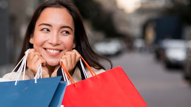 Mulher sorridente segurando sacolas de compras