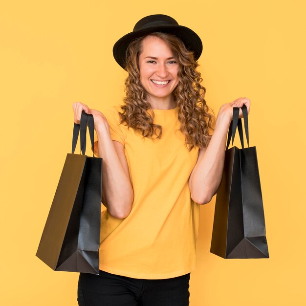 Mulher sorridente segurando sacolas pretas de compras na sexta-feira