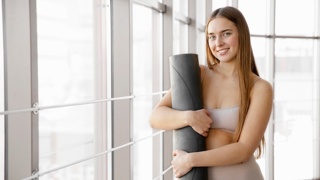 Foto grátis mulher sorridente segurando tapete de ioga