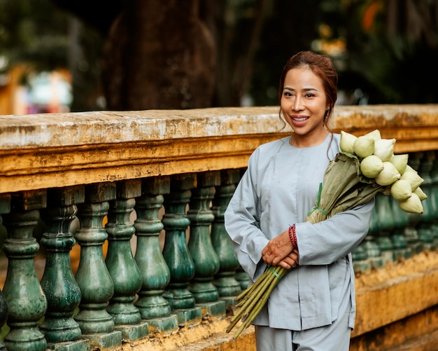 Mulher sorridente segurando um buquê de flores no templo