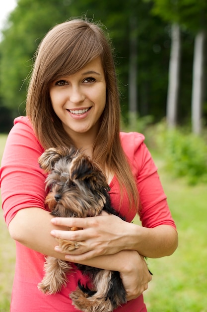 Foto grátis mulher sorridente segurando um cachorrinho fofo