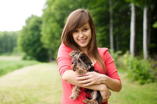 Foto grátis mulher sorridente segurando um cachorrinho fofo