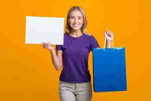 Foto grátis mulher sorridente segurando um cartaz em branco e uma sacola de compras