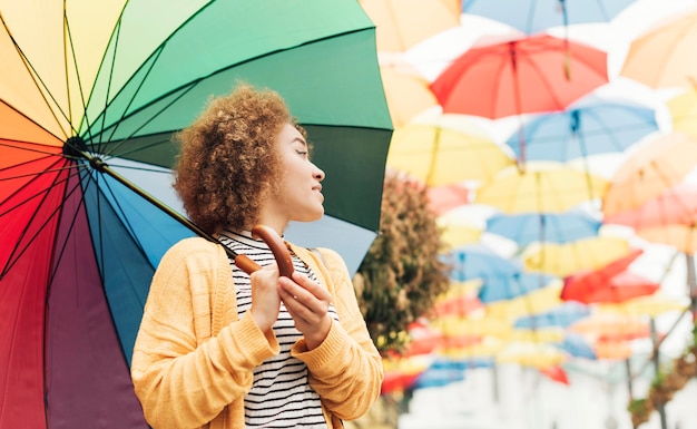 Mulher sorridente segurando um guarda-chuva arco-íris com espaço de cópia