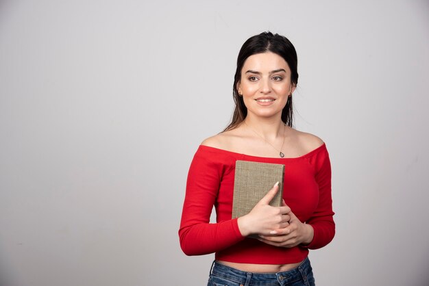 Mulher sorridente, segurando um livro e desviar o olhar.