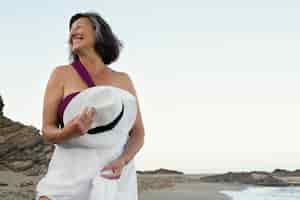 Foto grátis mulher sorridente sênior na praia aproveitando o dia