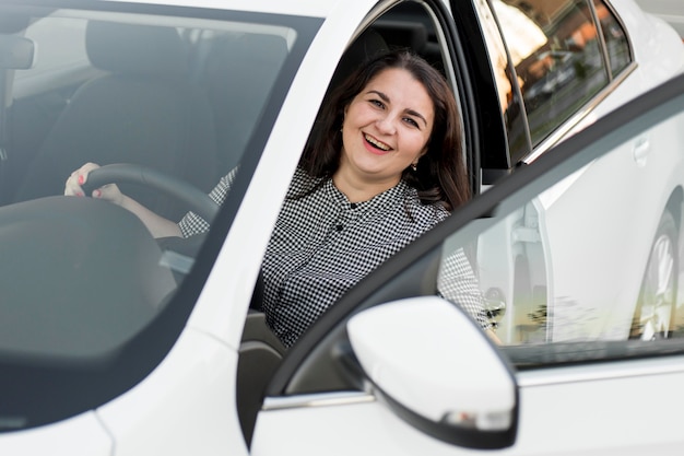 Foto grátis mulher sorridente sentada no banco do motorista