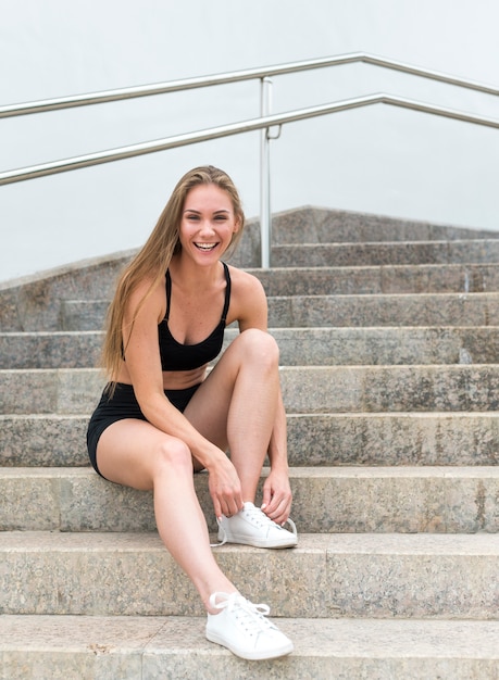 Mulher sorridente, sentado na escada tiro longo