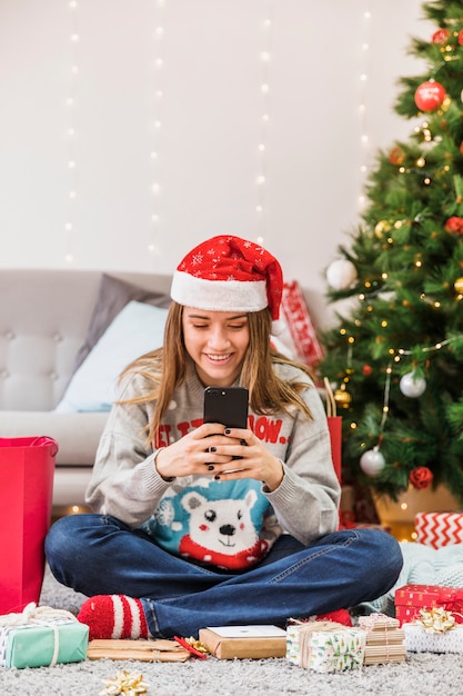 Mulher sorridente, texting, em, árvore natal