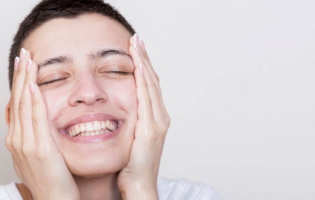 Mulher sorridente, tocando a pele do rosto macio