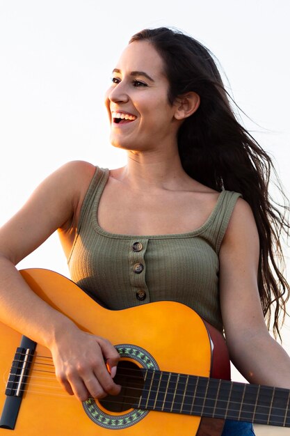 Mulher sorridente tocando guitarra ao ar livre na natureza