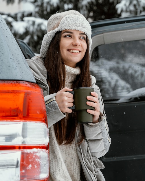 Mulher sorridente tomando uma bebida quente durante uma viagem