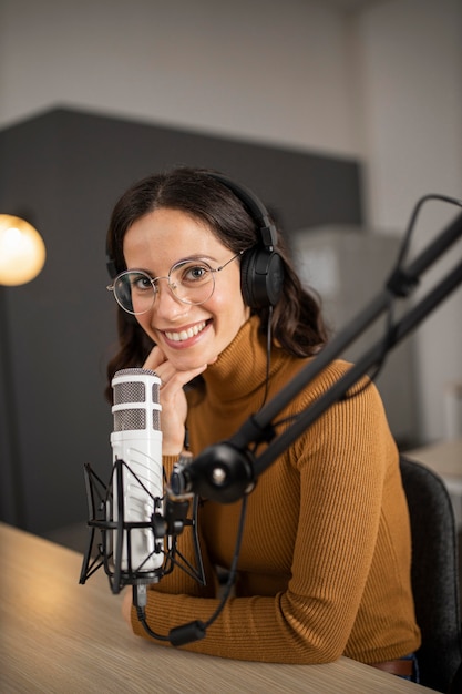 Foto grátis mulher sorridente transmitindo no rádio com fones de ouvido e microfone