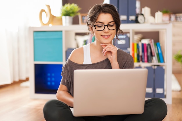 Foto grátis mulher sorridente usando laptop no chão de casa