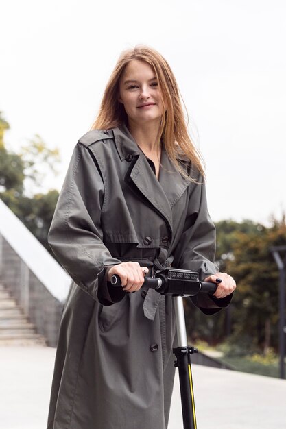 Mulher sorridente usando scooter elétrico ao ar livre