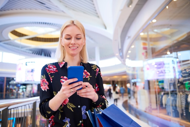 Mulher sorridente usando telefone celular em shopping