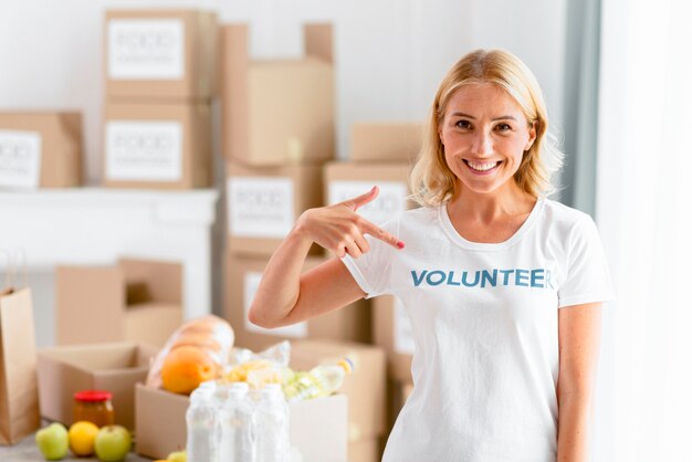 Mulher sorridente, voluntária posando enquanto aponta para sua camiseta