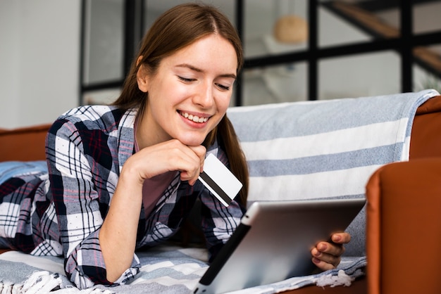 Mulher sorrindo e segurando um cartão de crédito