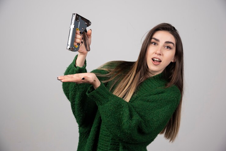 Foto grátis mulher surpreendida segurando uma ferramenta de trabalho em um fundo cinza.