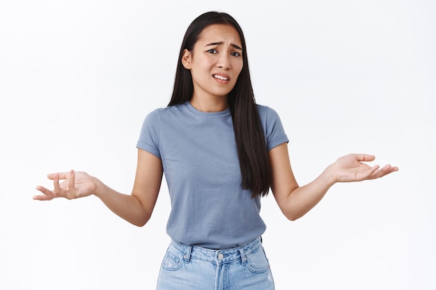 mulher tendo mal-entendido, não sei o que fazer, encolhendo os ombros com as mãos estendidas para o lado em consternação, franzindo a testa