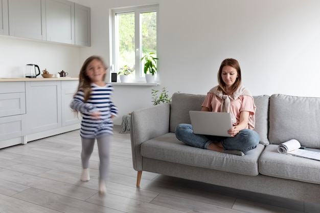 Mulher tentando trabalhar em um laptop de casa enquanto os filhos estão correndo