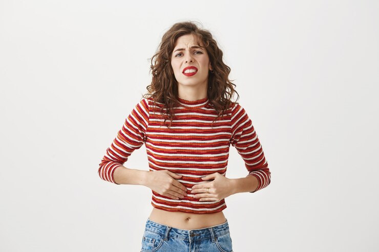 Foto grátis mulher teve intoxicação alimentar, sentindo-se mal, tocando o estômago e fazendo careta de dor