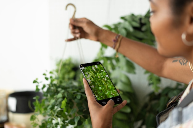 Mulher tira uma foto de uma planta de casa para compartilhar nas redes sociais