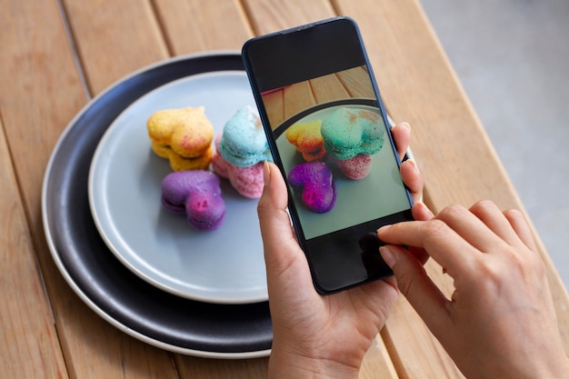 Mulher tirando fotos de macarons em forma de coração em aviões com smartphone