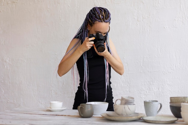 Mulher tirando fotos de utensílios de cerâmica em casa