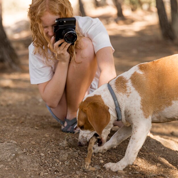 Mulher tirando fotos do cachorro mordendo uma tora