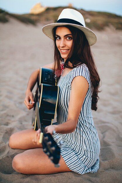 Foto grátis mulher tocando guitarra na areia