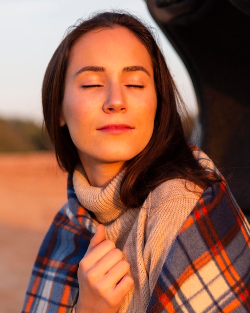 Foto grátis mulher tomando banho de sol com um cobertor enquanto está na natureza