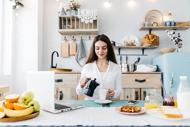 Mulher tomando café da manhã na cozinha