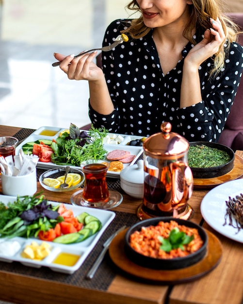 Mulher tomando café da manhã ovos mexidos com ervas legumes ervas e chá