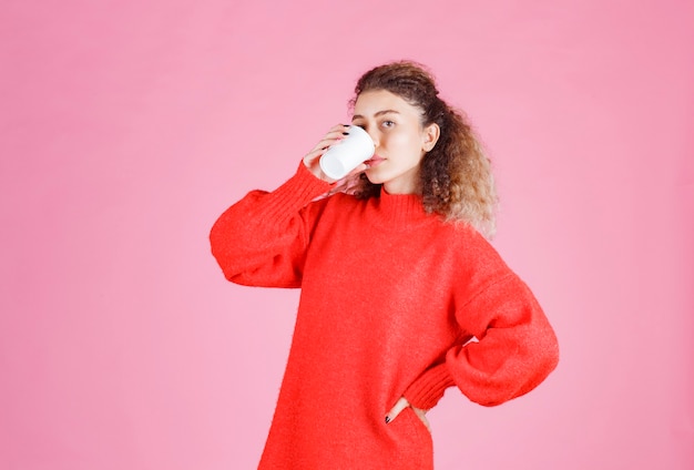 mulher tomando café em um copo descartável.