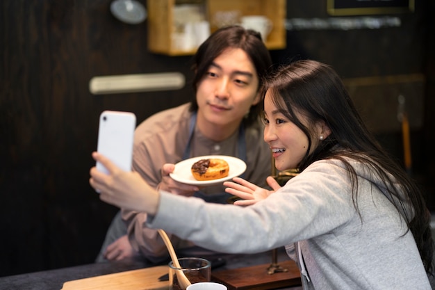 Mulher tomando selfie com homem e rosquinha em um restaurante