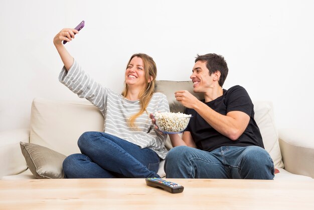 Mulher tomando selfie dela com namorado comendo pipocas