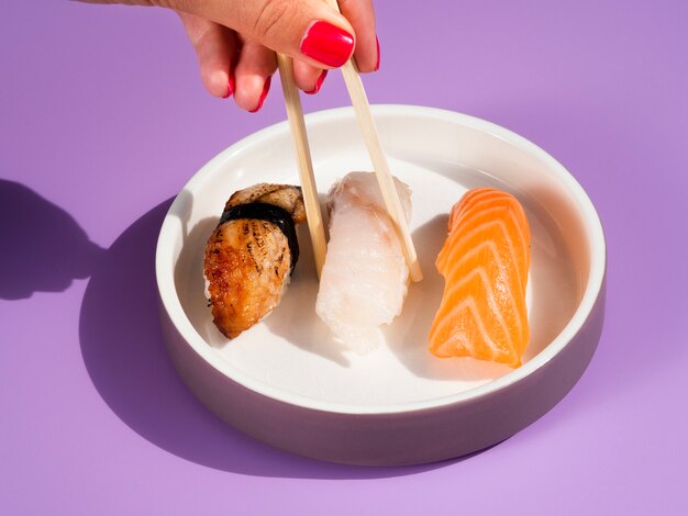 Mulher tomando sushi delicioso de um prato com sushi