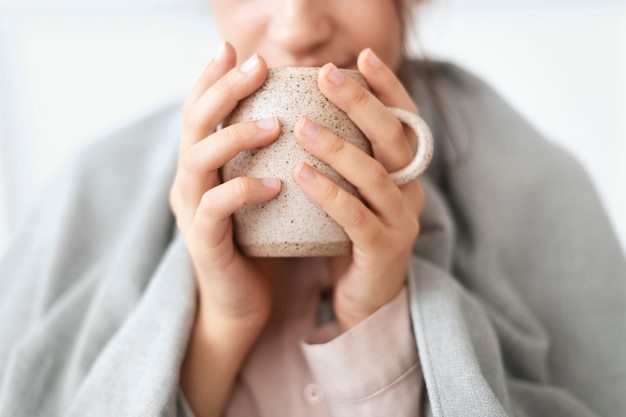 Mulher tomando um gole de chá da caneca durante o inverno