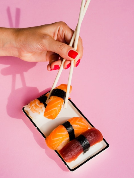 Mulher tomando um sushi de salmão do prato com sushi