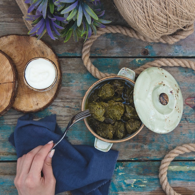 Mulher tomando um yarpaq dolmasi de uma panela branca cheia de dolma