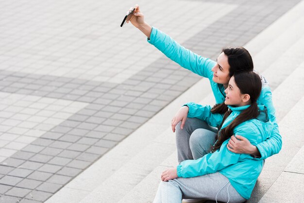 Mulher tomando uma selfie com a filha com espaço de cópia