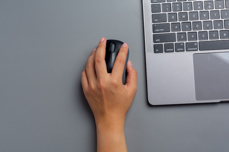 Foto grátis mulher trabalha com um laptop em casa e segura um mouse de computador na mão esquerda.