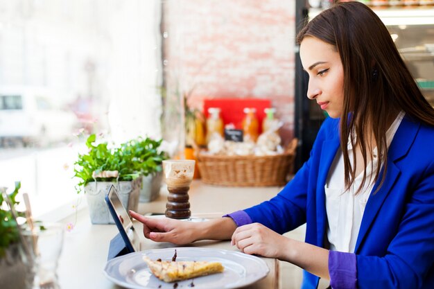 Mulher trabalha com um tablet na mesa em um café