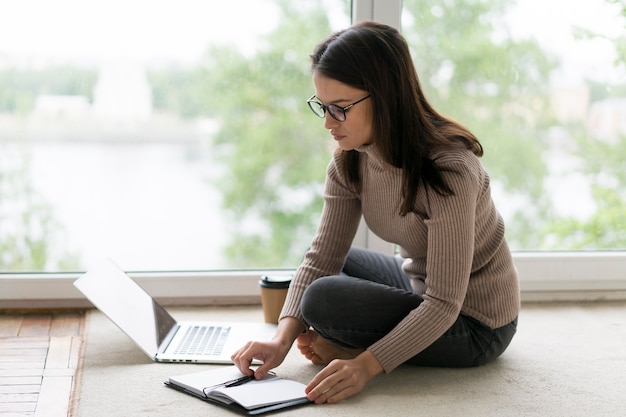 Mulher trabalhando em seu laptop no chão