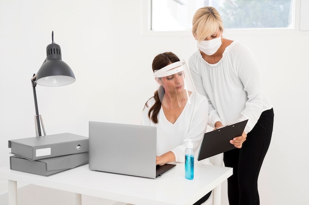 Mulher trabalhando em um escritório e usando proteção facial, vista frontal
