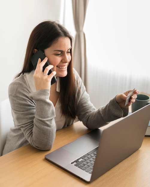 Mulher trabalhando no laptop e falando no telefone