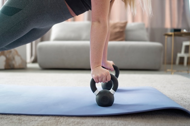 Foto grátis mulher treinando com kettlebell no tapete