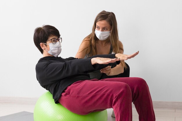 Mulher treinando em uma bola de fitness enquanto usava uma máscara médica